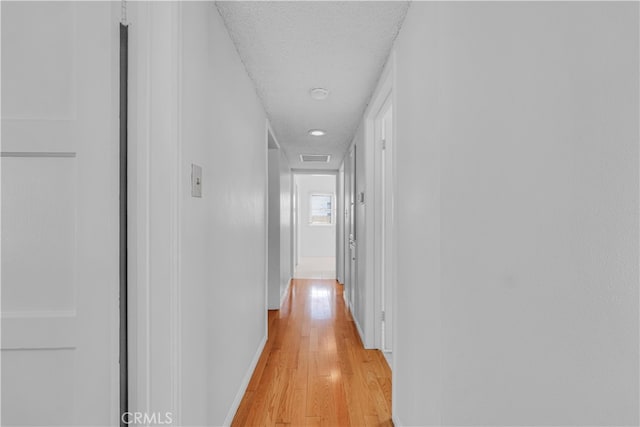 hallway with light wood-type flooring and baseboards