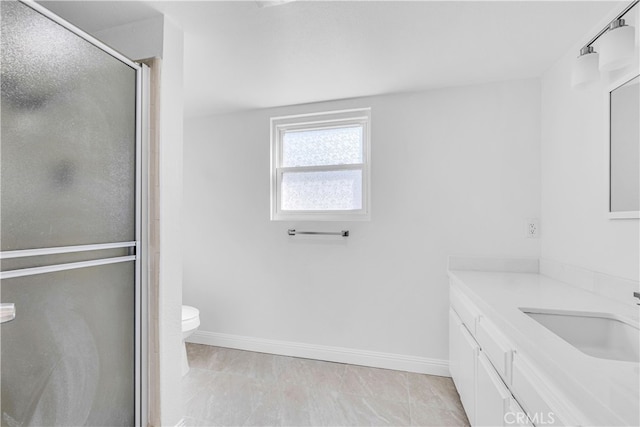 bathroom featuring toilet, a stall shower, vanity, and baseboards