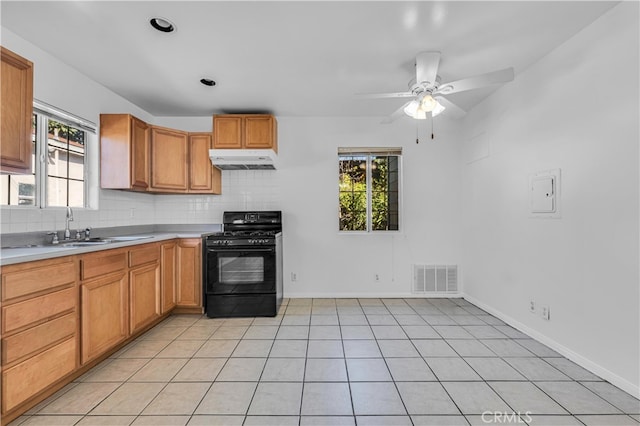 kitchen with visible vents, backsplash, under cabinet range hood, black gas range, and a sink