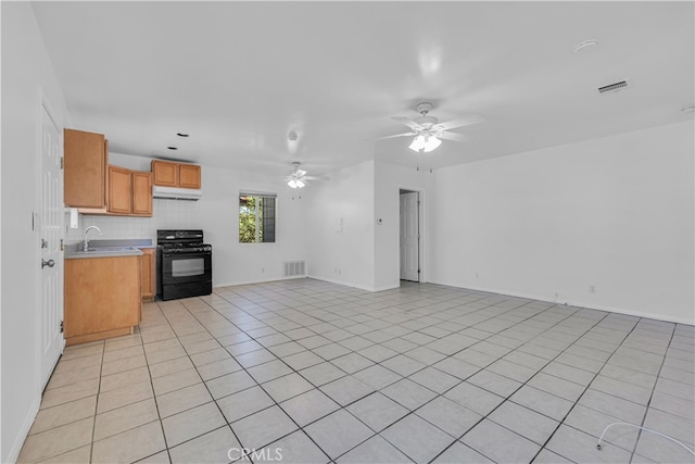 kitchen with under cabinet range hood, open floor plan, decorative backsplash, gas stove, and a sink