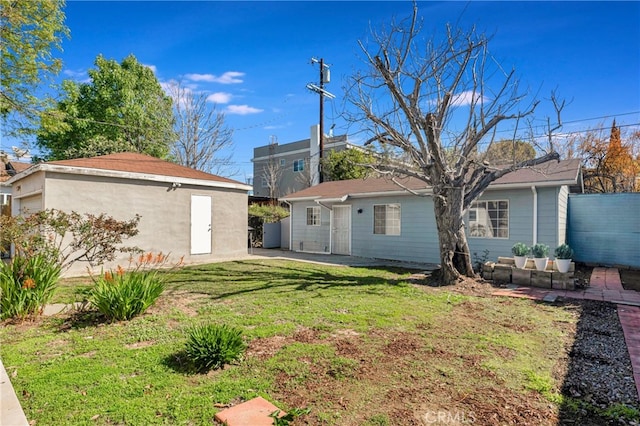 rear view of house featuring an outbuilding, a yard, and fence