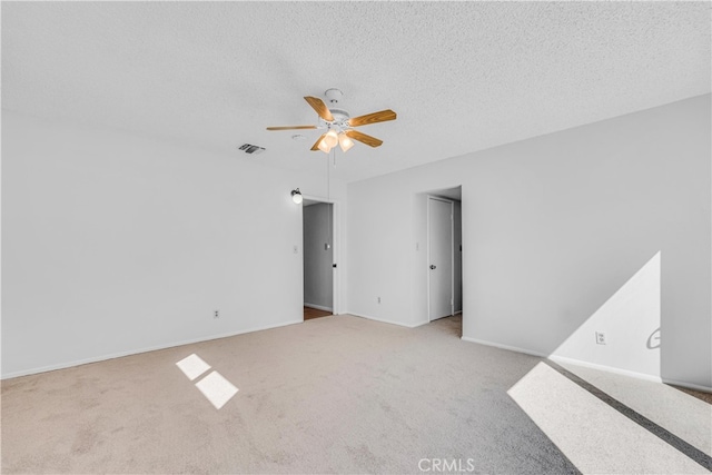 carpeted spare room with baseboards, a ceiling fan, visible vents, and a textured ceiling