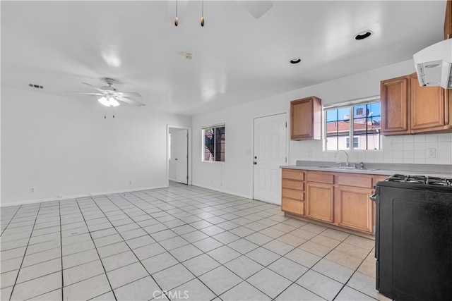 kitchen featuring a ceiling fan, a sink, tasteful backsplash, black gas range oven, and light countertops