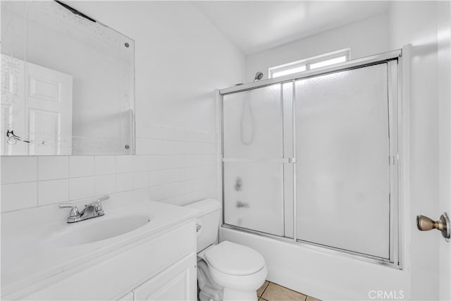 full bathroom featuring tile patterned flooring, toilet, vanity, enclosed tub / shower combo, and tile walls