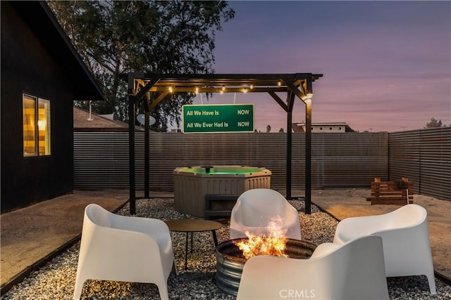 patio terrace at dusk featuring a fenced backyard and an outdoor fire pit