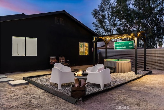 patio terrace at dusk featuring a fire pit and fence