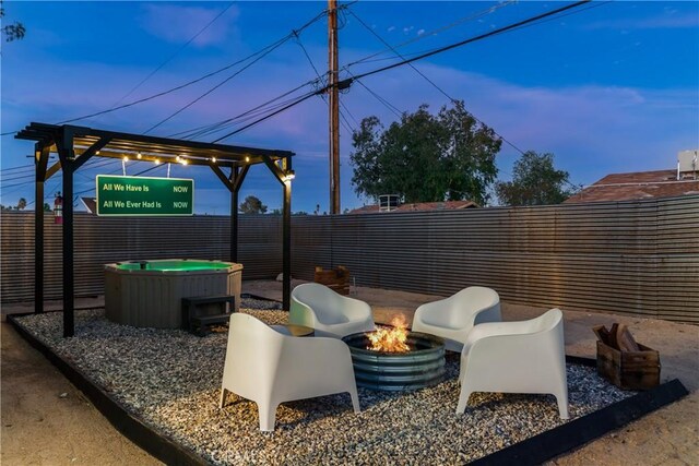 view of patio with an outdoor fire pit, a hot tub, and a fenced backyard