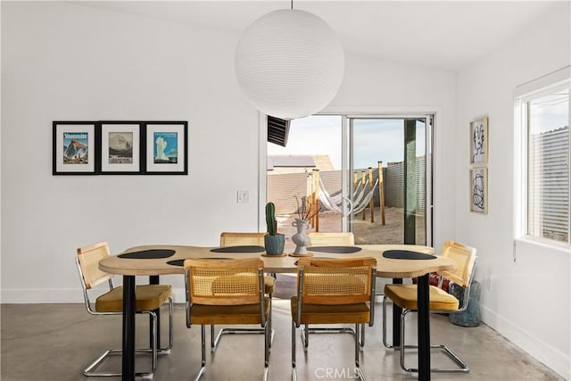 dining space featuring concrete flooring and baseboards