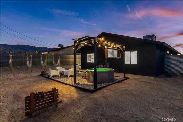 back of house at dusk featuring a patio, fence, and a pergola