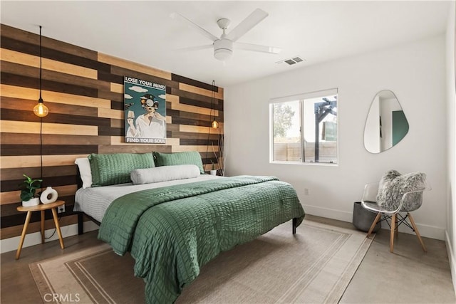 bedroom with an accent wall, wooden walls, baseboards, and visible vents