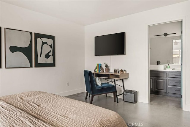 bedroom featuring a sink, connected bathroom, baseboards, and finished concrete floors