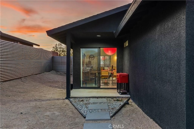 entrance to property with stucco siding and fence