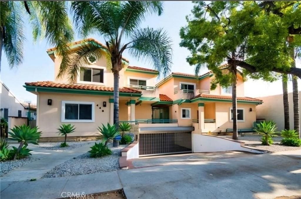 mediterranean / spanish house with stucco siding, fence, and a tile roof