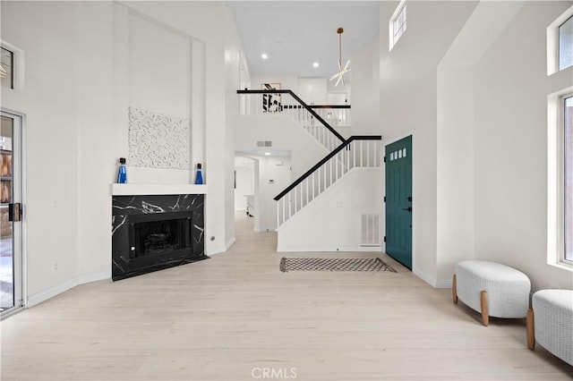 living area featuring visible vents, wood finished floors, a high end fireplace, stairway, and a high ceiling