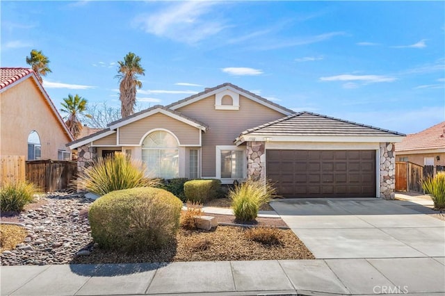 view of front of property with stone siding, concrete driveway, an attached garage, and fence