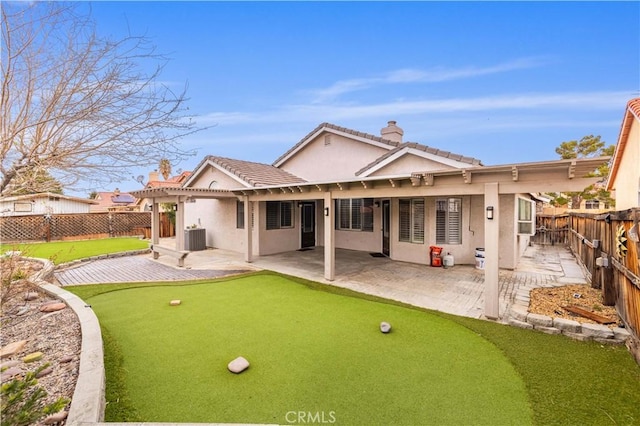 rear view of house with a fenced backyard, central AC, and stucco siding