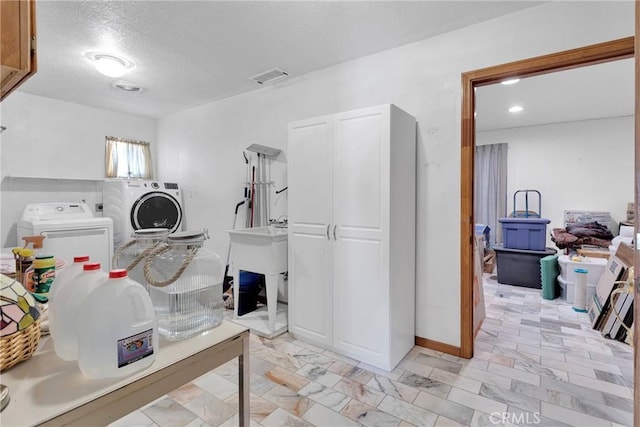 laundry area featuring visible vents, laundry area, a sink, a textured ceiling, and washer and clothes dryer