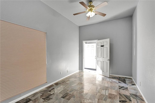 unfurnished room with a ceiling fan, baseboards, and a textured wall