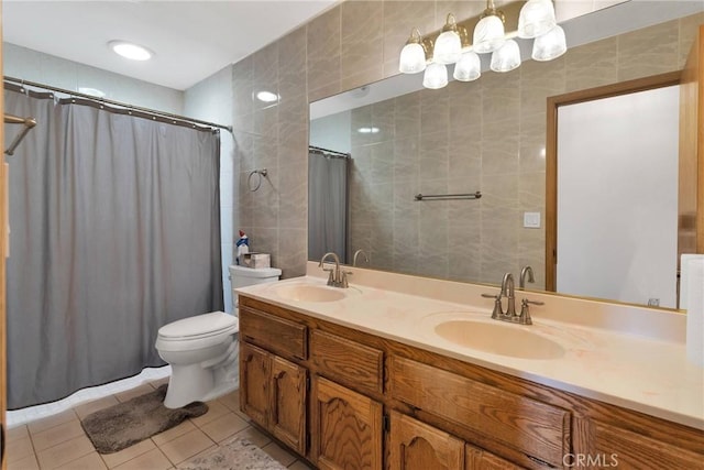 bathroom featuring tile patterned floors, toilet, tile walls, and a sink