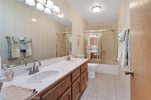 bathroom featuring a sink, toilet, tile walls, and tile patterned flooring