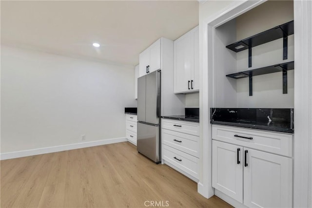 kitchen featuring dark countertops, white cabinets, light wood-type flooring, and freestanding refrigerator