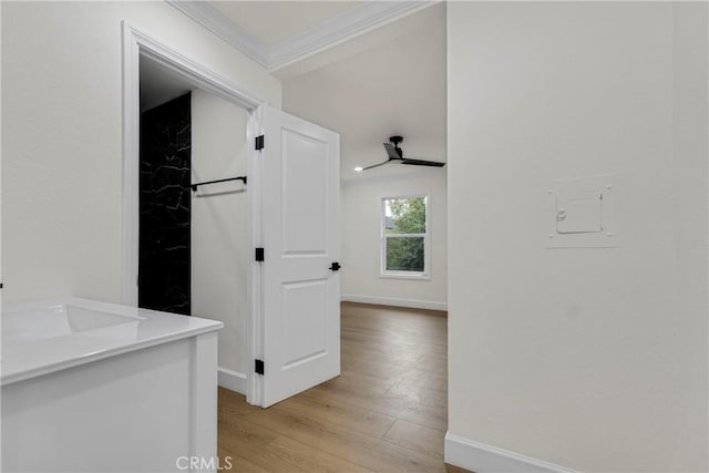 corridor with light wood-style flooring, baseboards, and ornamental molding