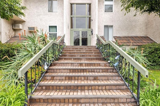 entrance to property featuring an AC wall unit and stucco siding