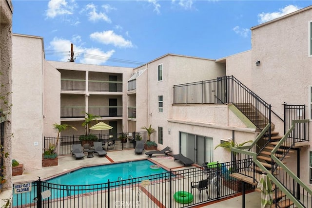 community pool with stairway, a patio, and fence