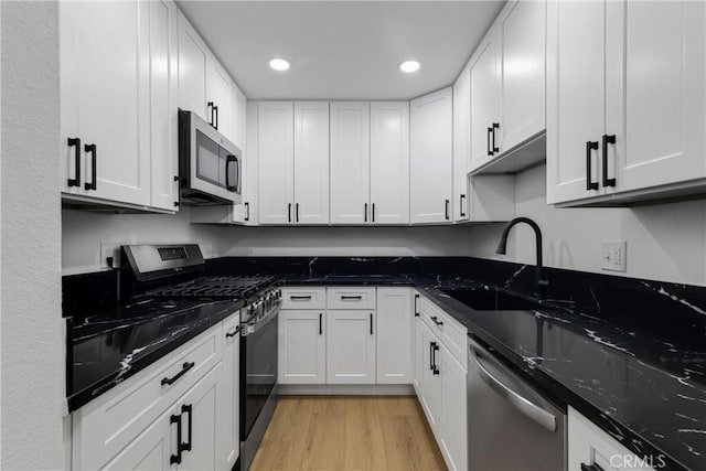 kitchen with light wood-style flooring, a sink, recessed lighting, appliances with stainless steel finishes, and white cabinets