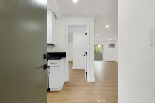 hall featuring light wood finished floors, crown molding, baseboards, an AC wall unit, and recessed lighting