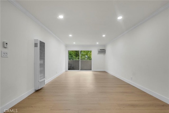 empty room with light wood-type flooring, a heating unit, crown molding, and baseboards