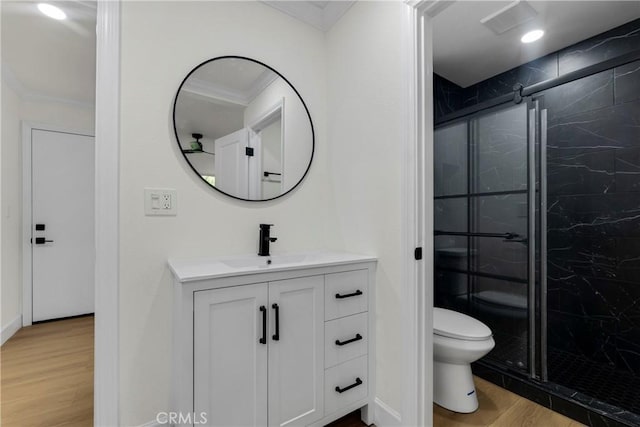 bathroom with a marble finish shower, crown molding, toilet, wood finished floors, and vanity