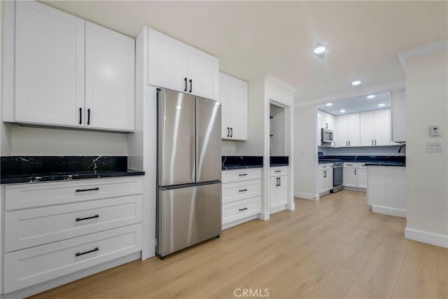 kitchen with dark countertops, white cabinets, light wood-type flooring, and appliances with stainless steel finishes