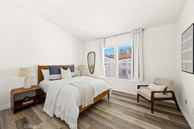 bedroom featuring vaulted ceiling, wood finished floors, and baseboards