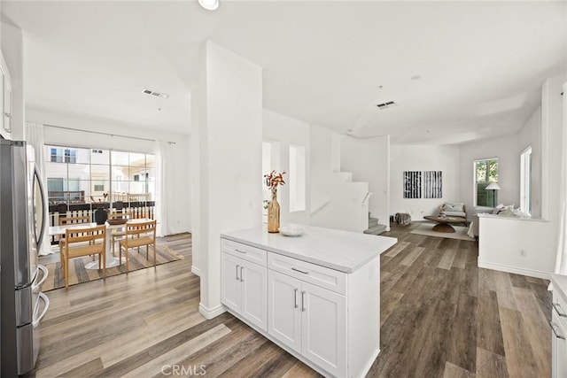 kitchen featuring visible vents, wood finished floors, open floor plan, white cabinetry, and freestanding refrigerator