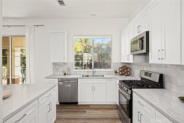 kitchen with visible vents, dark wood-style flooring, a sink, stainless steel appliances, and white cabinetry