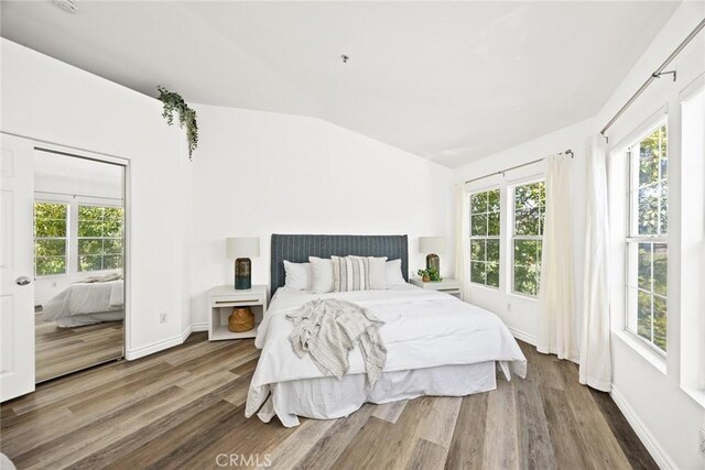 bedroom featuring baseboards, lofted ceiling, and wood finished floors