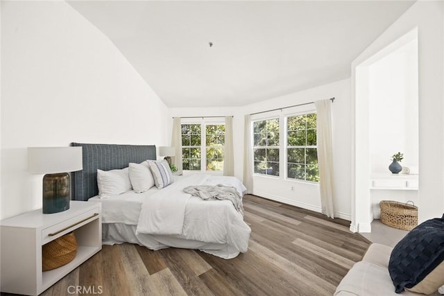 bedroom featuring lofted ceiling, wood finished floors, and baseboards