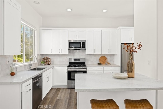 kitchen with decorative backsplash, appliances with stainless steel finishes, a kitchen bar, and a sink