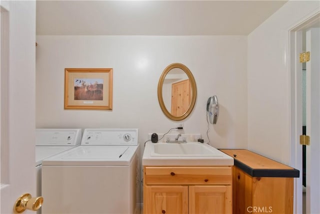 clothes washing area featuring a sink, cabinet space, and washing machine and clothes dryer