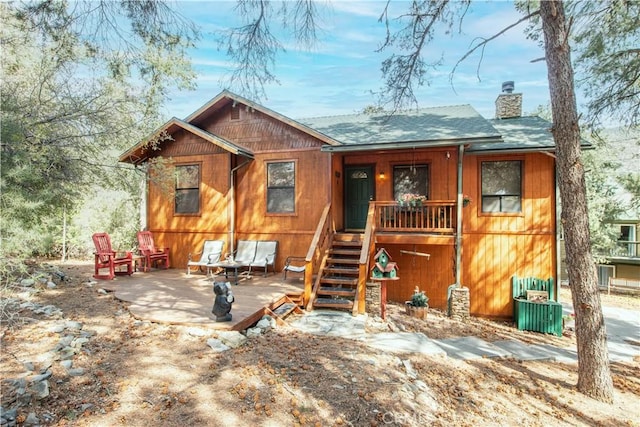 view of front of property with a porch, a chimney, and a shingled roof