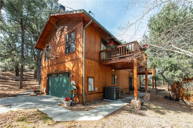 view of side of property featuring central air condition unit, driveway, a wooden deck, and a garage