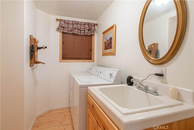 washroom featuring light wood finished floors, washer and dryer, baseboards, and a sink