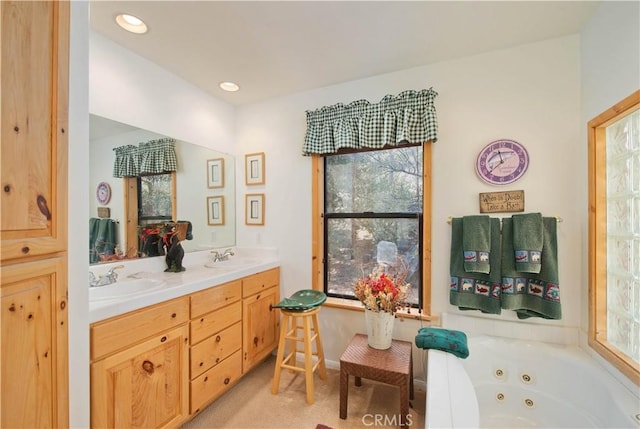 full bathroom with double vanity, a jetted tub, recessed lighting, and a sink