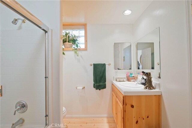 full bath featuring toilet, wood finished floors, recessed lighting, shower / bath combination with glass door, and vanity