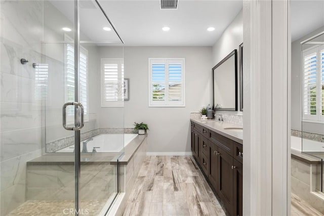 full bath with double vanity, a garden tub, visible vents, and a stall shower