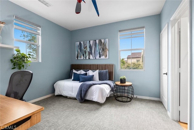 carpeted bedroom featuring multiple windows, baseboards, and visible vents