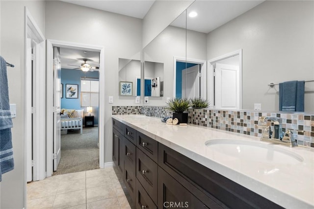 ensuite bathroom with tile patterned flooring, double vanity, backsplash, and a sink