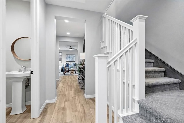 stairway featuring a ceiling fan, wood finished floors, and baseboards