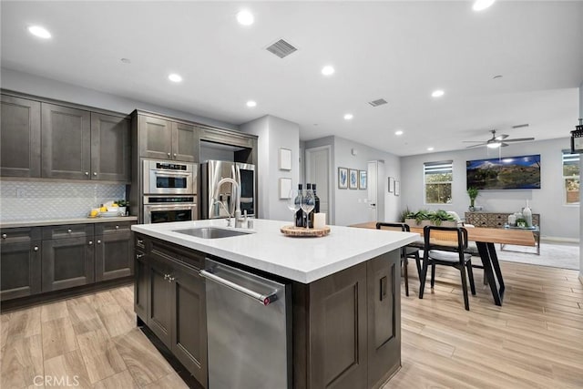 kitchen with light wood-type flooring, visible vents, backsplash, stainless steel appliances, and light countertops